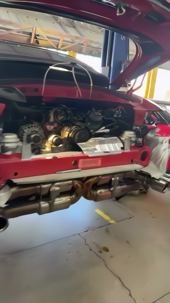 A Porsche raised on the lift with the rear suspension and exhaust exposed.